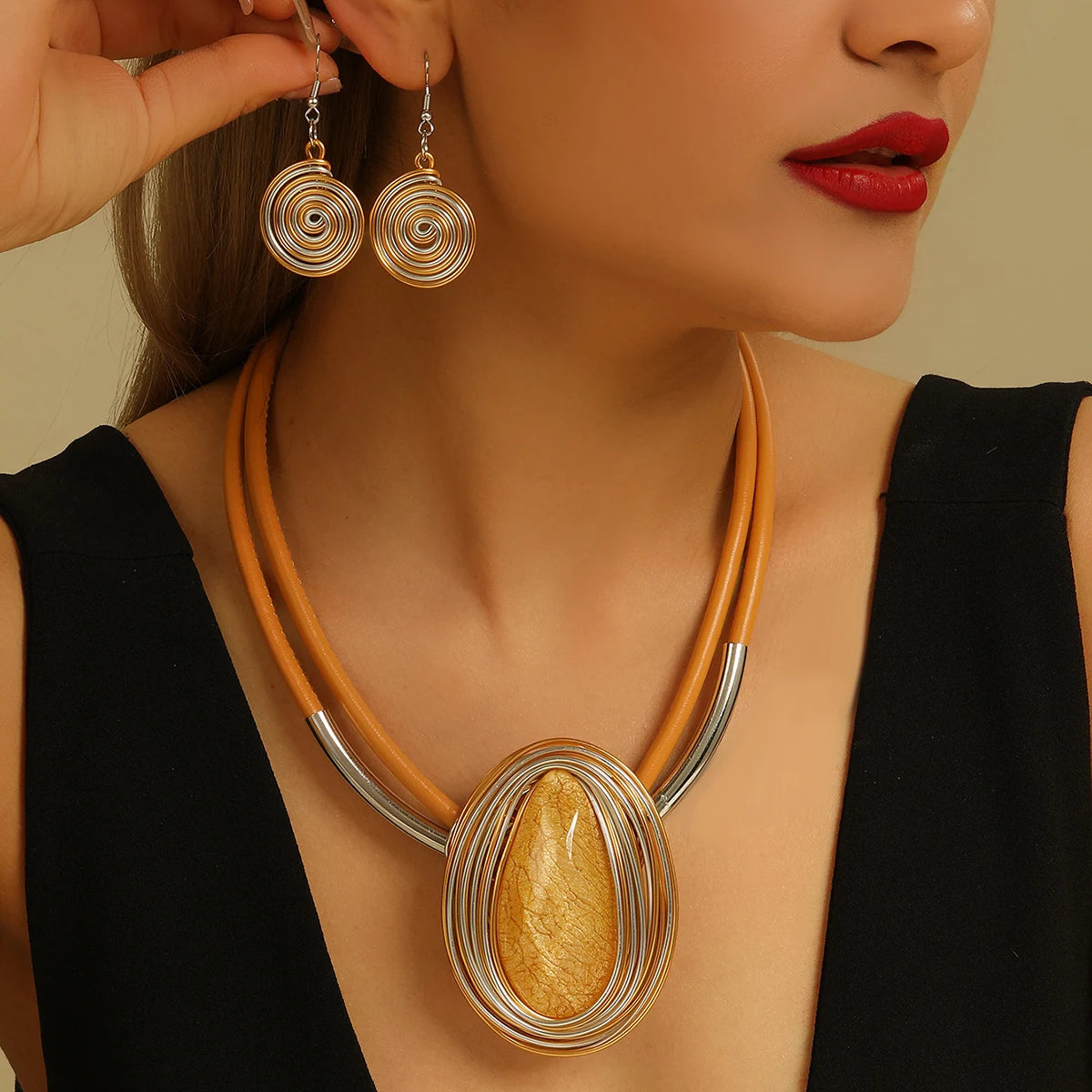 Woman wearing a gold necklace and earrings against a beige background
