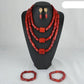 Red beaded jewelry set including necklace, earrings, and bracelets on a black stand.