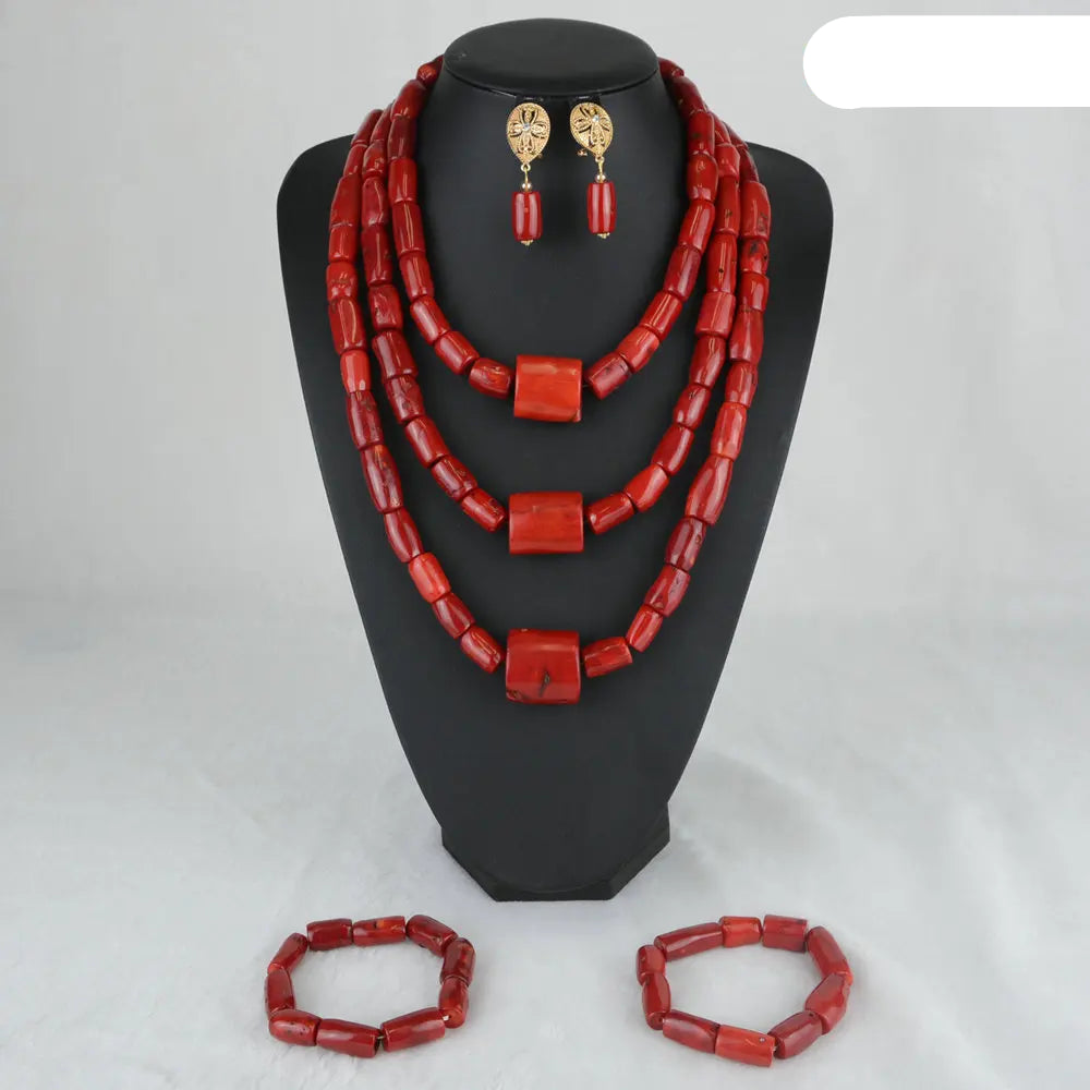 Red beaded jewelry set including necklace, earrings, and bracelets on a black stand.