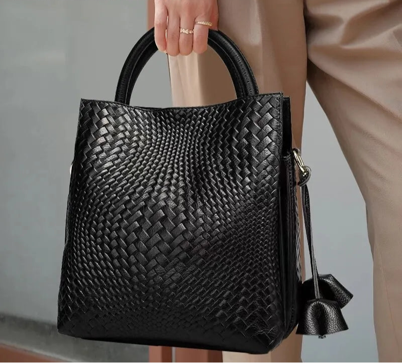 model holding black woven pattern handbag