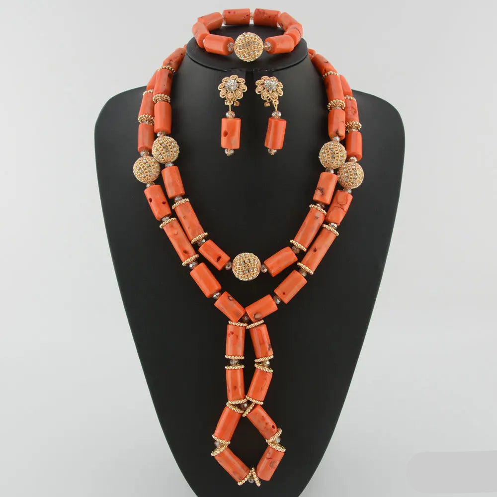 Jewelry set with orange beads and gold accents on a black stand