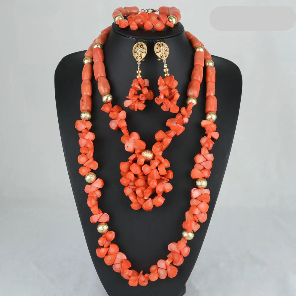Red coral jewelry set with necklace, earrings, and bracelet on a black stand.