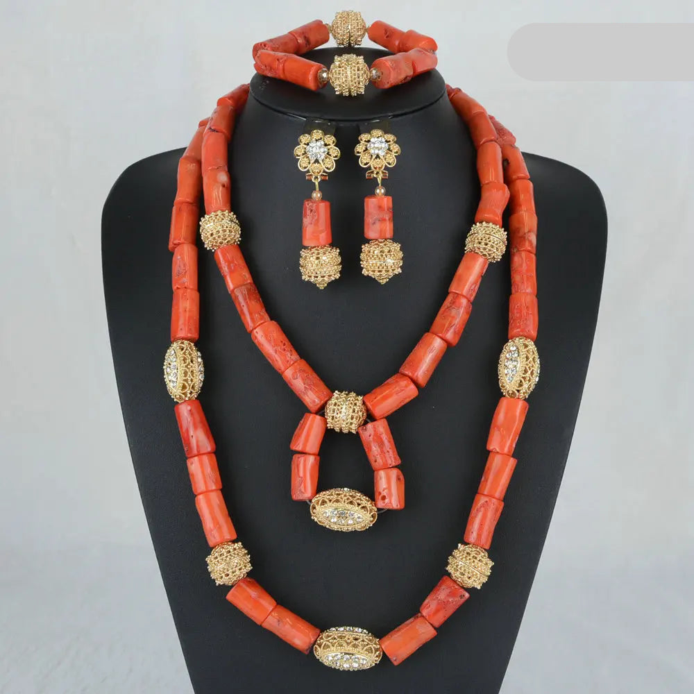 Red coral jewelry set with gold accents on a mannequin against a gray background.