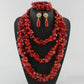 Red coral jewelry set on a black stand with a white background