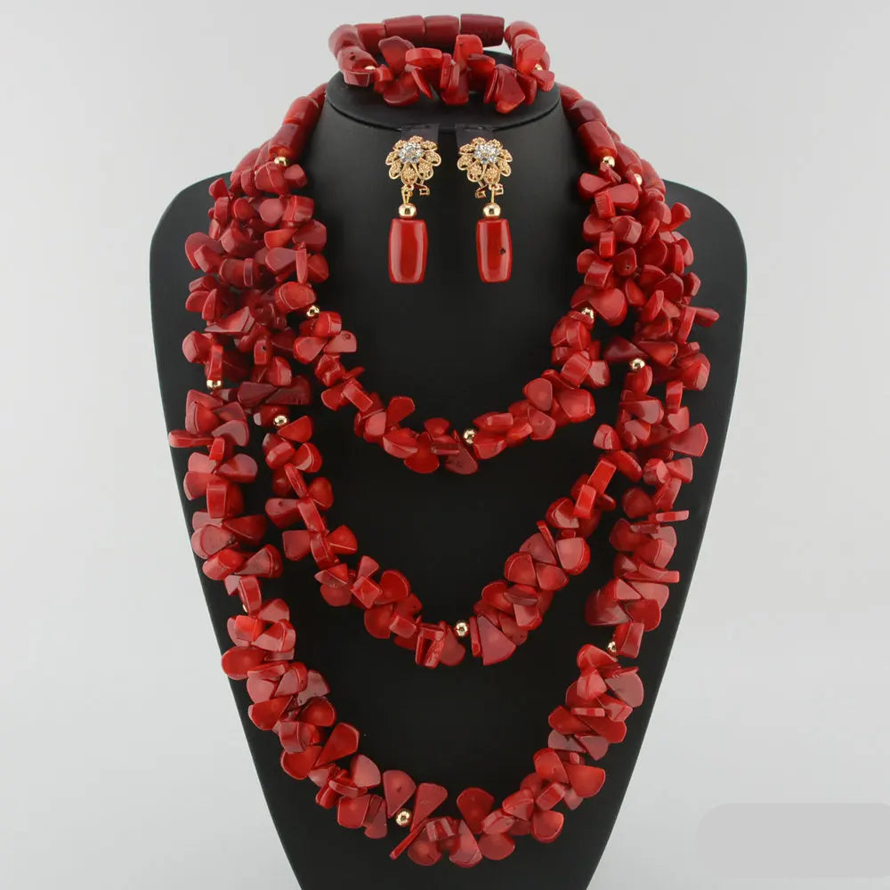 Red coral jewelry set on a black stand with a white background