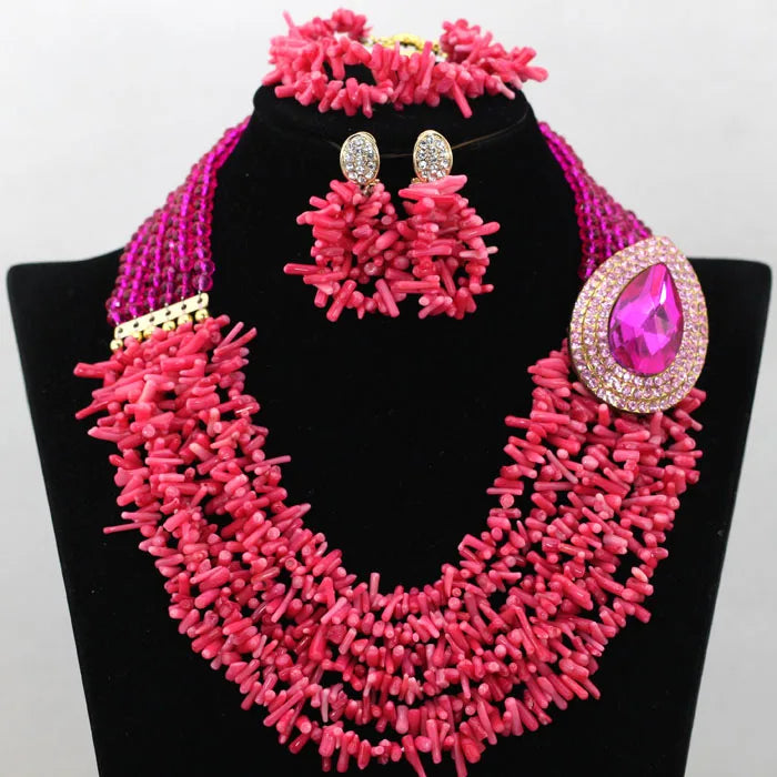 Pink beaded necklace and earrings set on a black stand with a white background