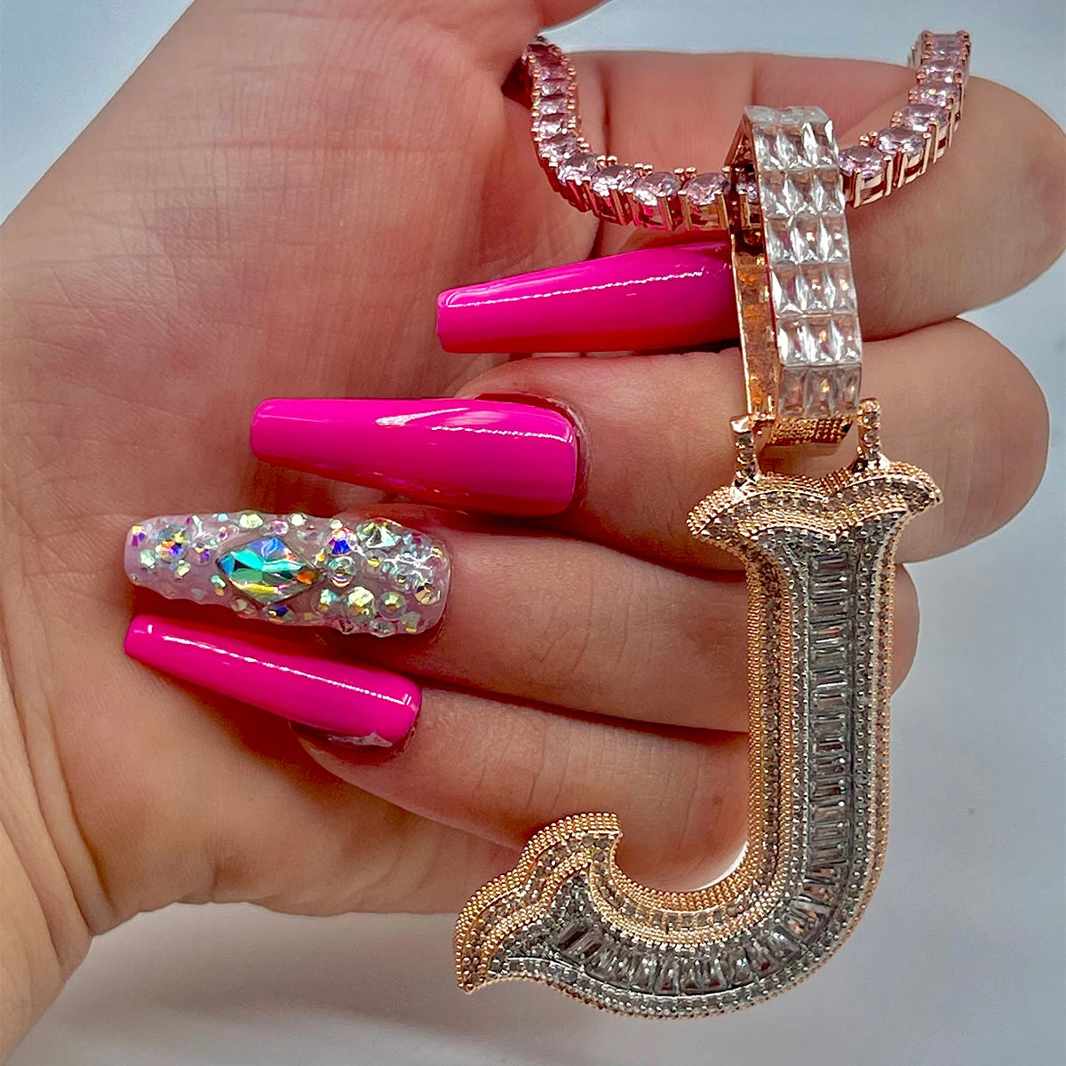 Hand with pink nails holding a large diamond-studded ring