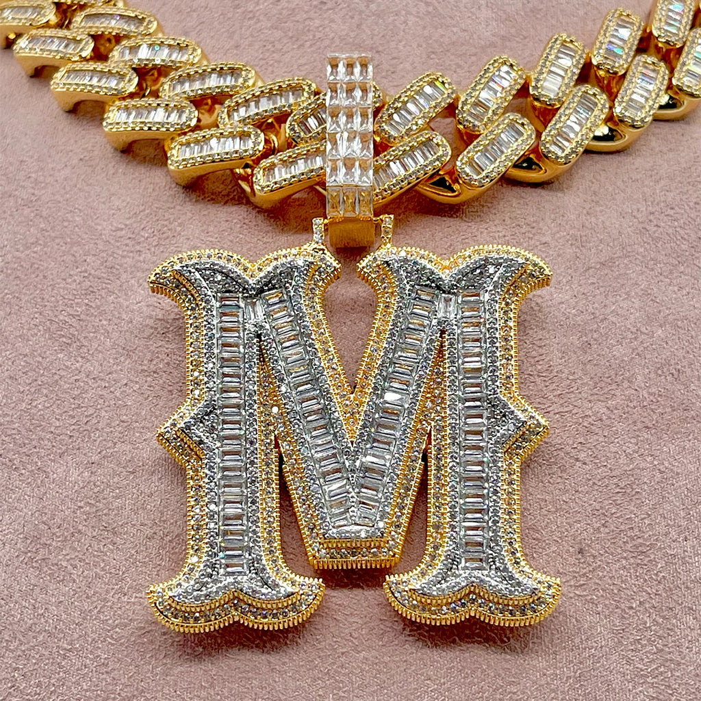 Gold and silver letter 'M' pendant on a pink background