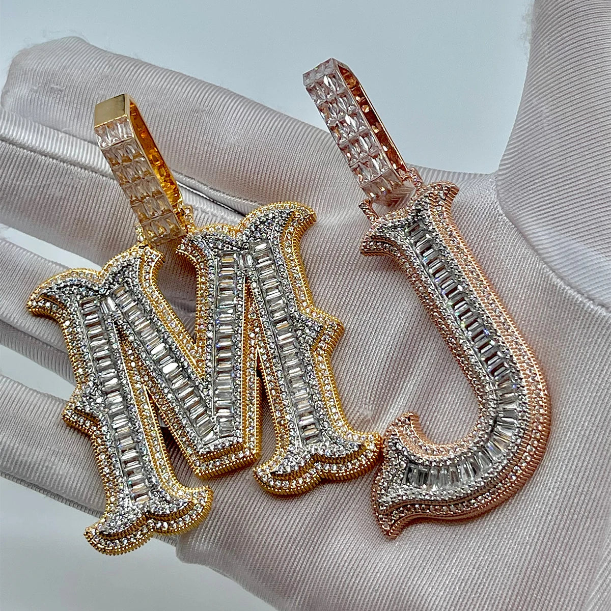 Decorative letters 'M' and 'N' with gemstone-like embellishments on a textured surface.