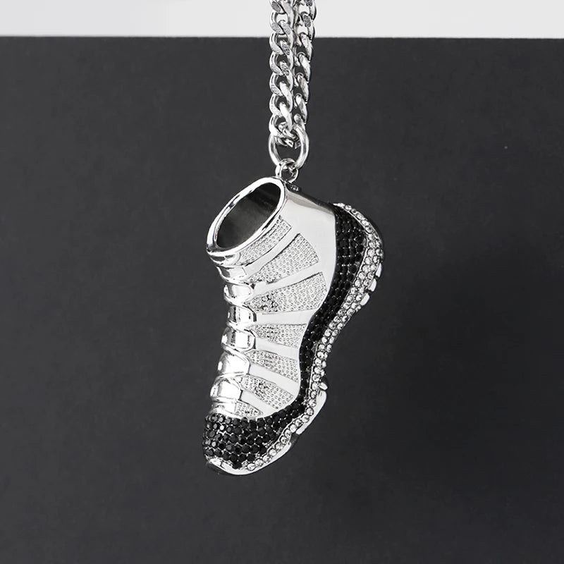 Silver sneaker pendant with black accents on a chain against a black background
