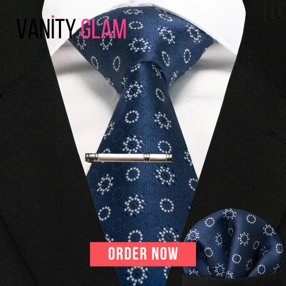 Blue patterned tie with matching pocket square and tie clip on a suit, with 'Vanity Glam' branding.